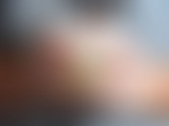 A person in a blue printed shirt holding a steaming cup of coffee, symbolizing the morning coffee ritual.