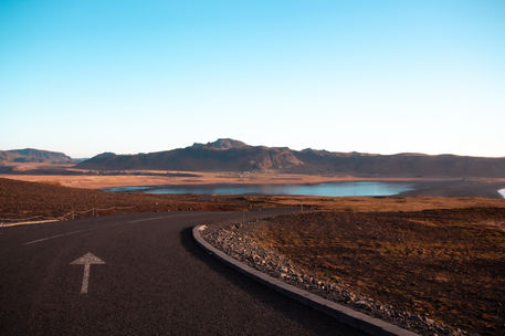 The road from Dyrhólaey, in the early morning light. An arrow on the road points east, towards Reynisfjara Beach and Vik