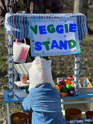 Child at a VEGGIE STAND with toy vegetables