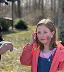 Young girl with strawberry face paint and earring outdoors