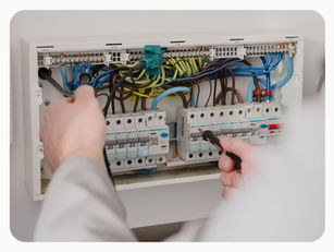 Electrician working safely inside a residential consumer unit during an electrical inspection and testing.