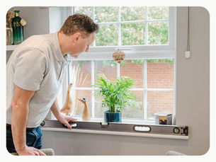 Surveyor using a spirit level to check the alignment of a window during a new-build snagging inspection.