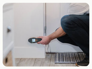Surveyor using a moisture meter to check a wall for signs of damp near an external door.