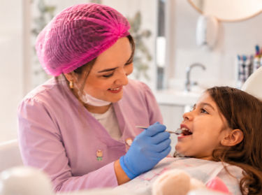 dentista infantil sorridente atendendo criança em sp