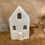 Thumbnail: White ceramic house tea light illuminated