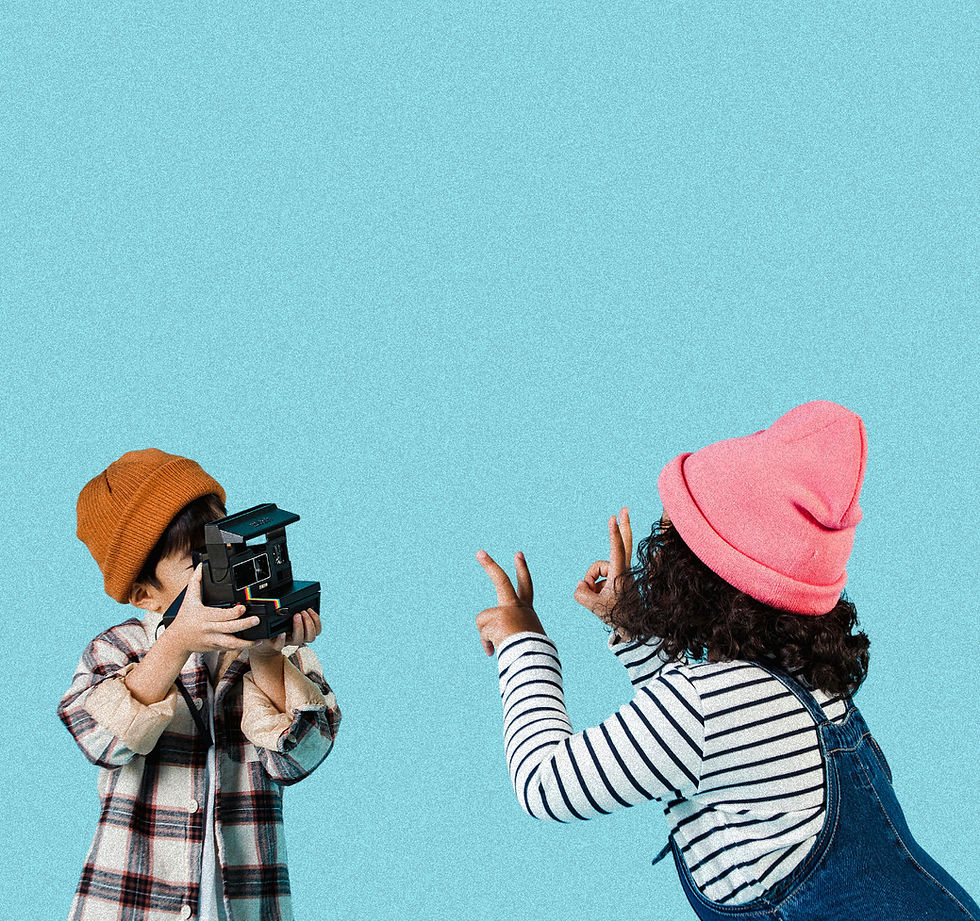 Deux enfants, un garçon tenant un appareil photo comme s'il prenait une photo, et une fille faisant un signe de paix avec les doigts.