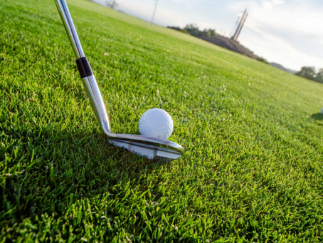 A golfer about to hit a golf ball on bright green turf