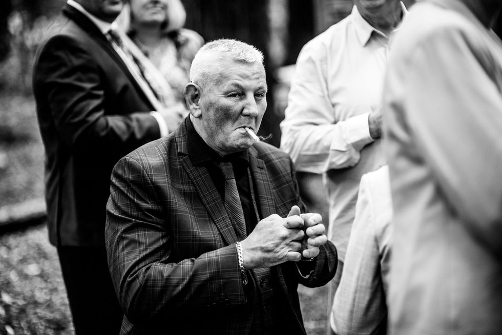 Man in suit smoking cigarette at wedding