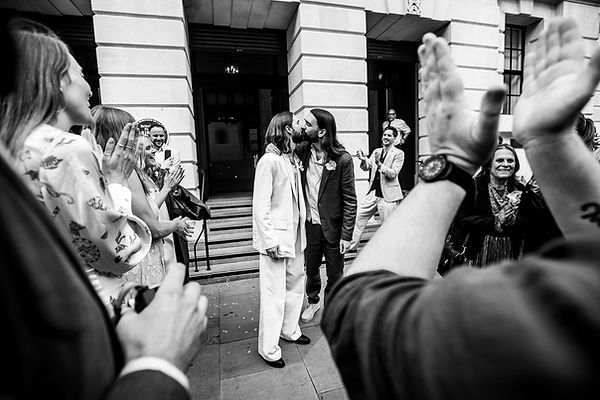 First kiss for 70's style lgbtq couple outside Camden Town Hall for registry wedding.