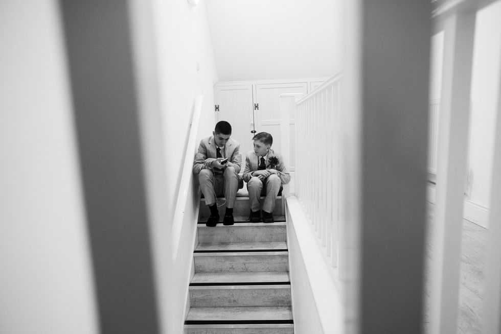 Two boys sit on stairs, looking at phones