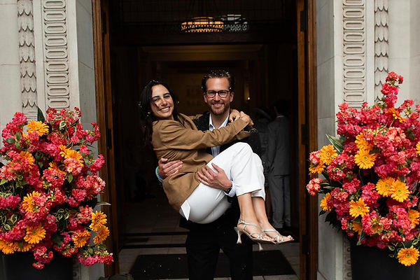 Old Marylebone Town Hall steps a groom holds bride in his arms.