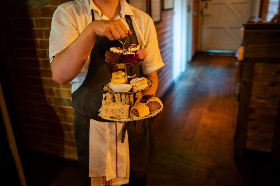 Server holding a tiered afternoon tea stand at a wedding.