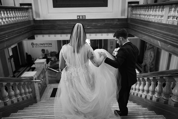Groom holds Brides hands as the walk down stairs of Islington Town Hall wedding.