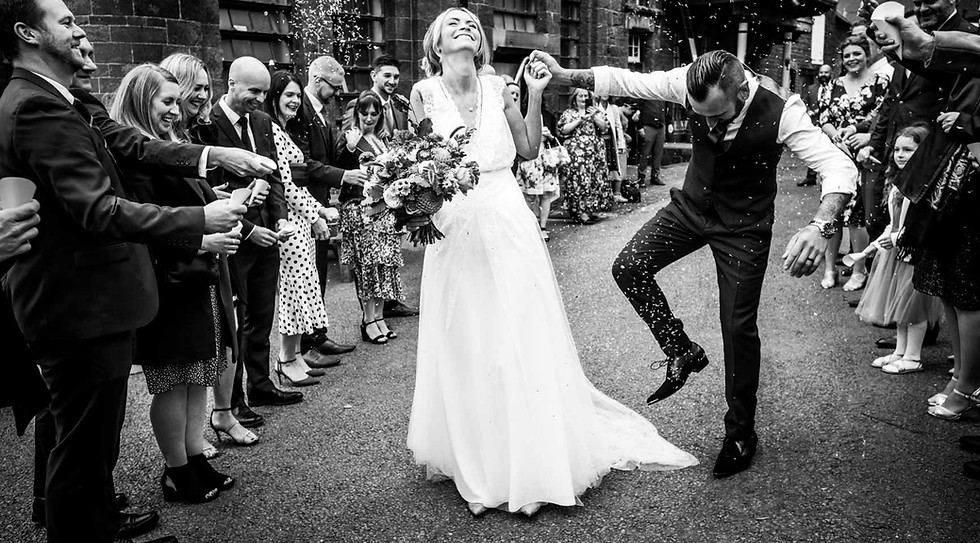 Groom trips on wedding gown while walking through confetti with bride loving aloud