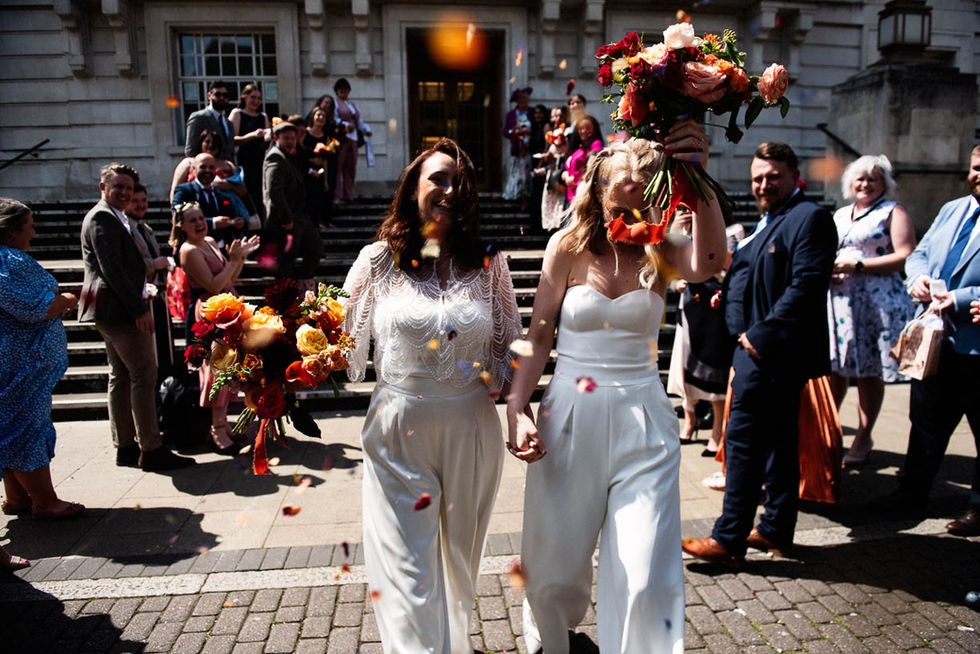 Happy lesbian couple exiting ceremony, confetti