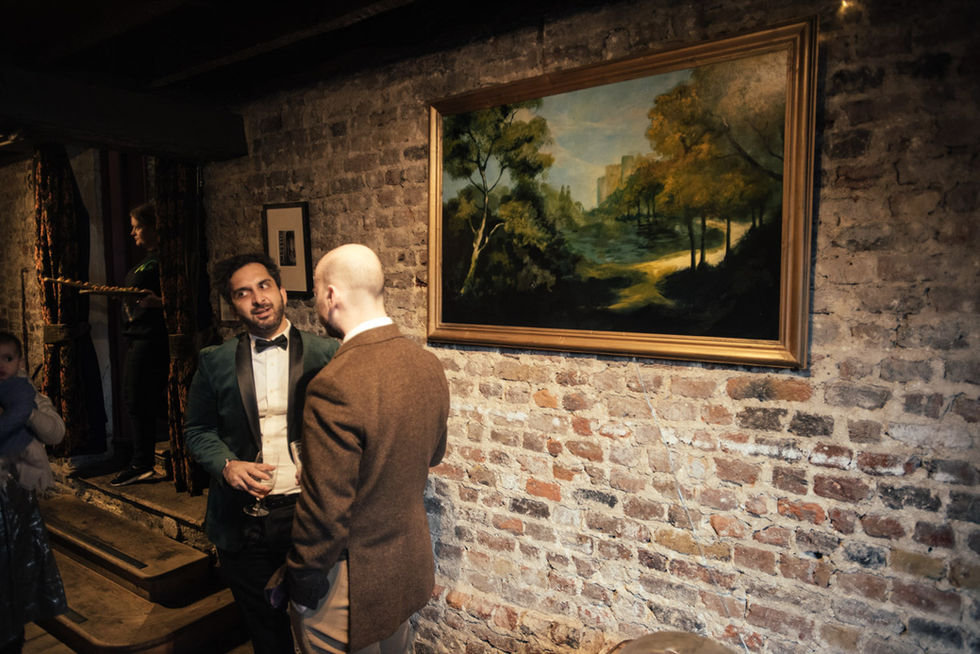 Two men converse near landscape painting