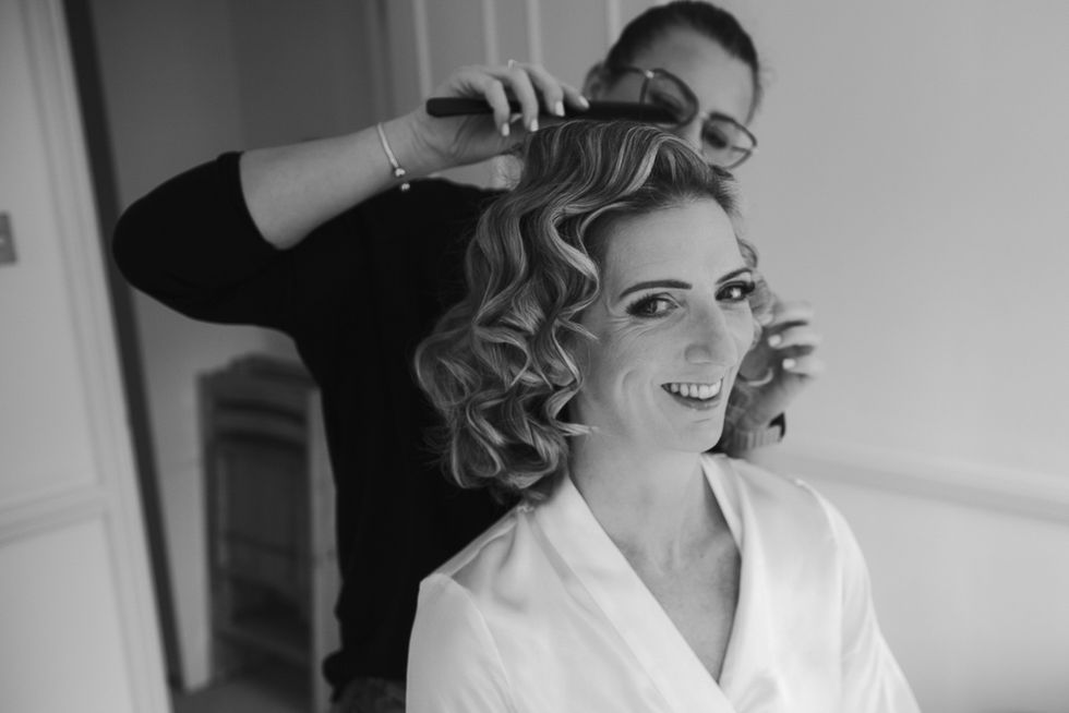 Bride smiling while having hair styled while wearing night gown