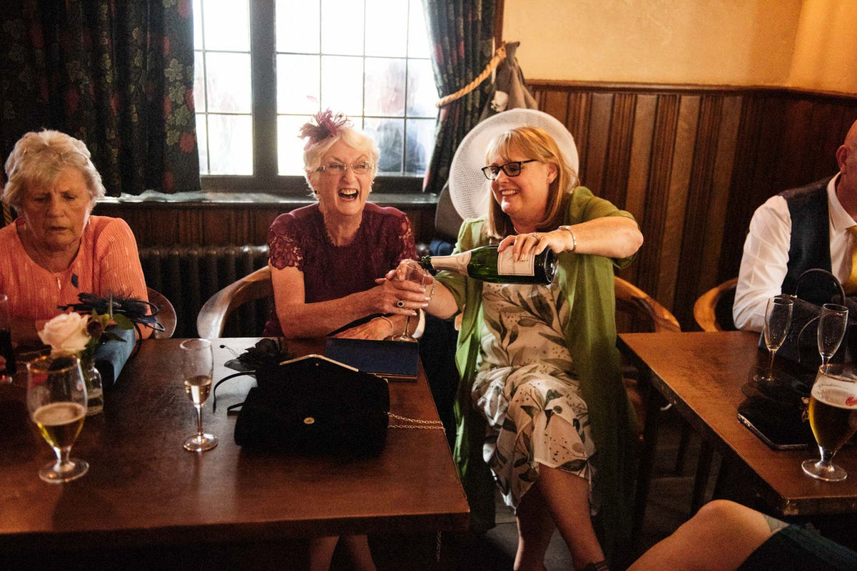 Happy guests opening champagne at wedding reception