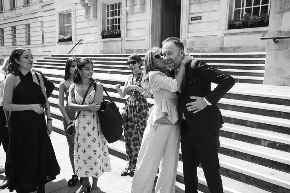 Couple embraces before ceremony, guests watch.