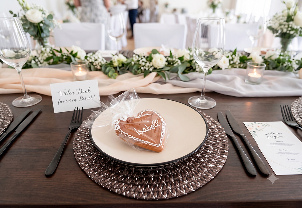 Personalisiertes Lebkuchenherz mit Namen als Tischkarte und Gastgeschenk auf einer gedeckten Hochzeits-Festtafel