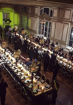 Overhead view of an elegant formal dinner in a grand ornate ballroom.