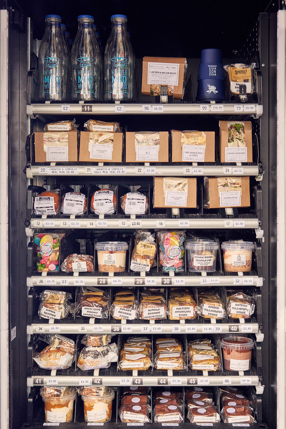 Vending machine with sandwiches, snacks, cookies, and drinks, each labeled with prices.