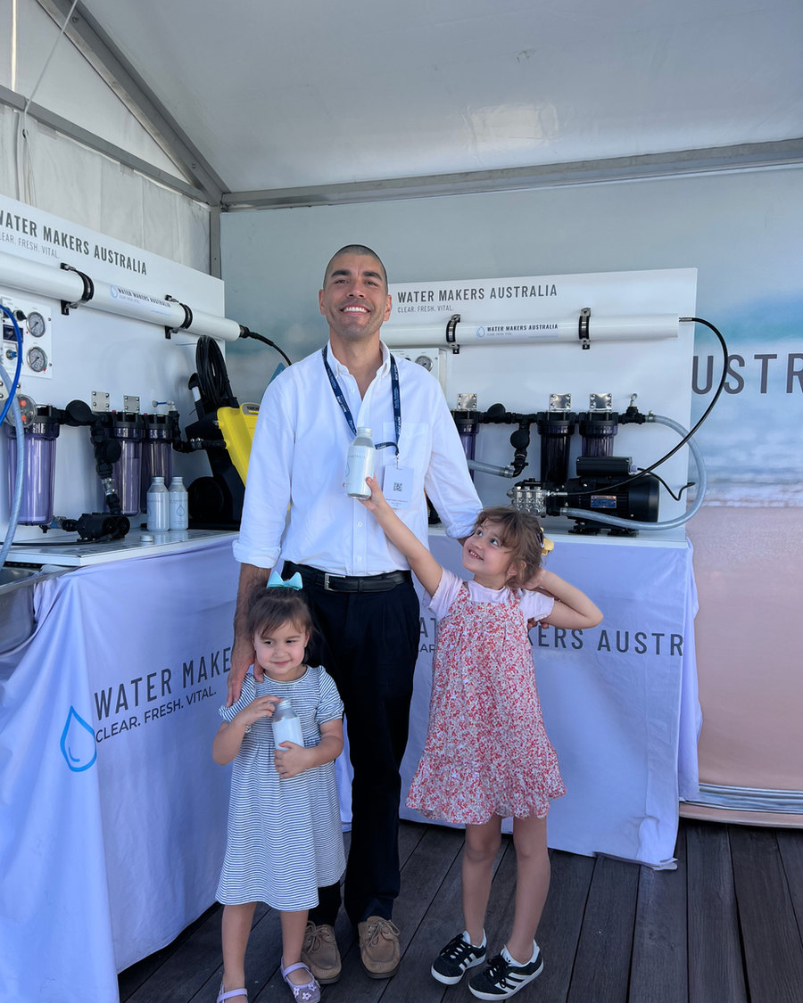 A Water Makers Australia specialist with his daughters at the company's boat show stand, complete systems on display behind.