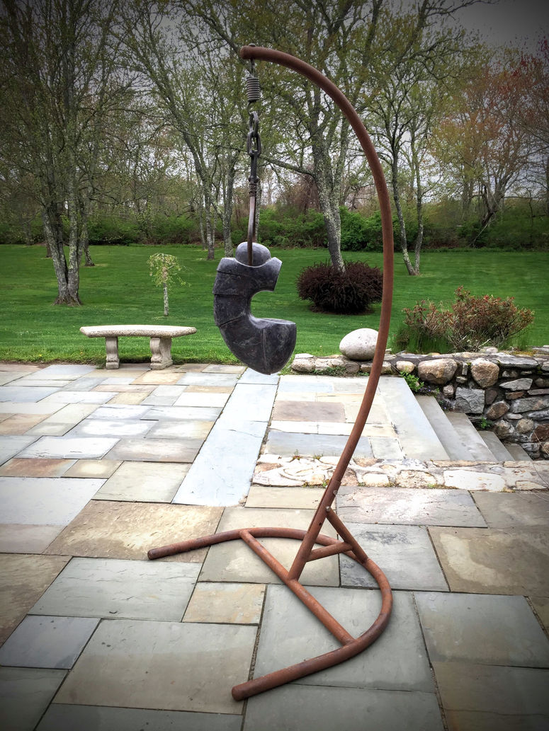 Image of Radio City Black Marble figurative sculpture named, Talisman by sculptor Greg Spitzer. hangs from skid tongs on fabricated steel hanger.