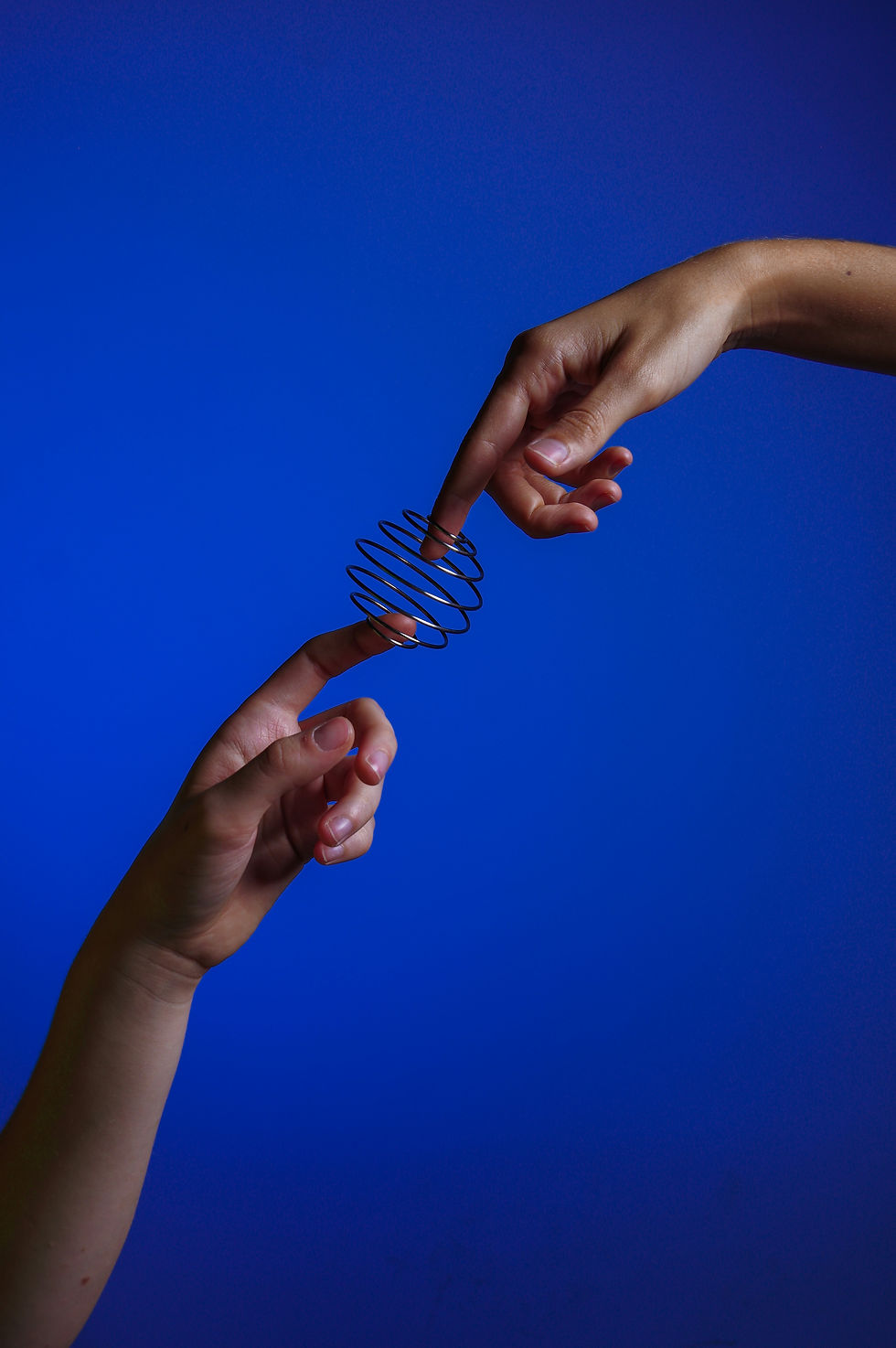 Two hands pointing at each other, their pointer fingers connected by a spiral.