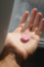 Close-up of a hand holding a pink, heart-shaped candy labeled "feelings".