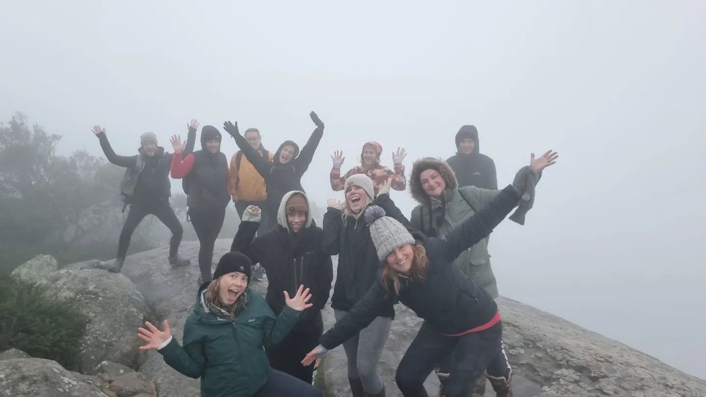 Misty morning with a group of women on top of a boulder, views are obscured by close clouds