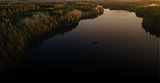 Picture of a beautiful lake with dark black water surrounded by trees late in the evening as the sun is setting. AI generated image.