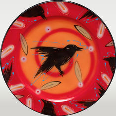 Red round ceramic plate with a black crow in the middle. Partial crow images decorate the rim