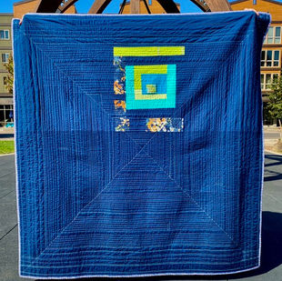 Back of quilt in blues and green; mostly blue with small squares in one corner