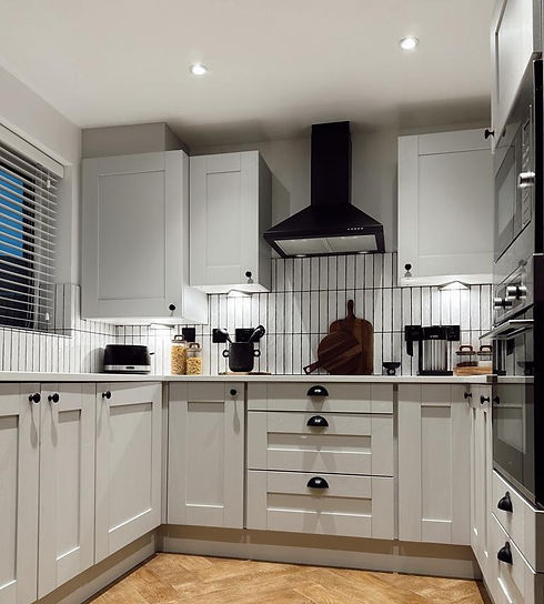 Refurbished kitchen with white cupboards and tiles and down lights installed under cupboards