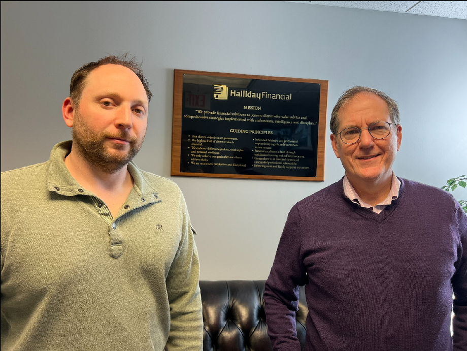 Two professionals standing in front of the Halliday Financial plaque.