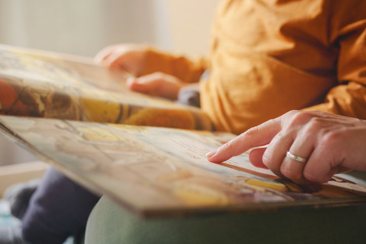 Adult and child reading a picture book together.