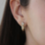 A young woman wearing the stunning gold earring with 8 moissanite gemstones. The elegant sparkle complements her youthful cha