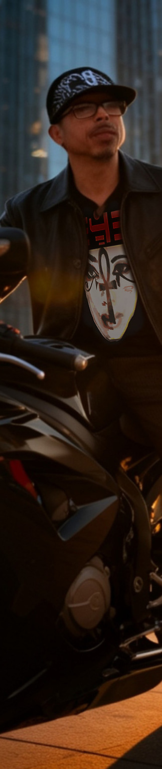 NIPPAWAS MOON Aloqwin's designer sitting on a black motorcycle with an ALOQWIN designer cap and black v-neck tee with Ankh'd design
