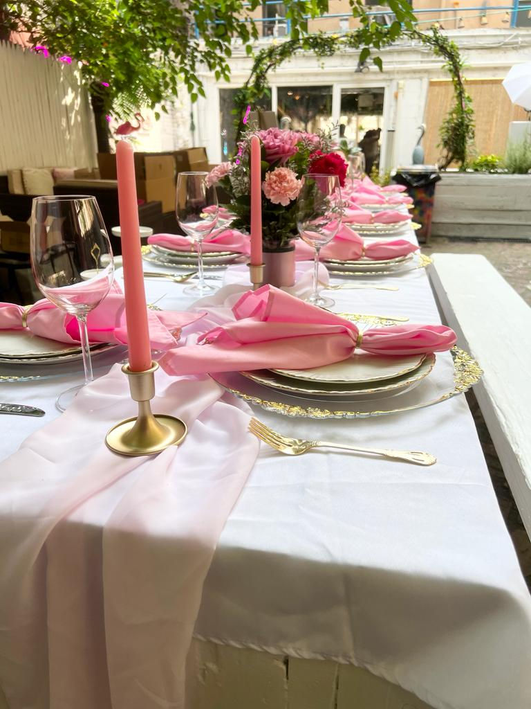 a table with pink napkins and candles on it