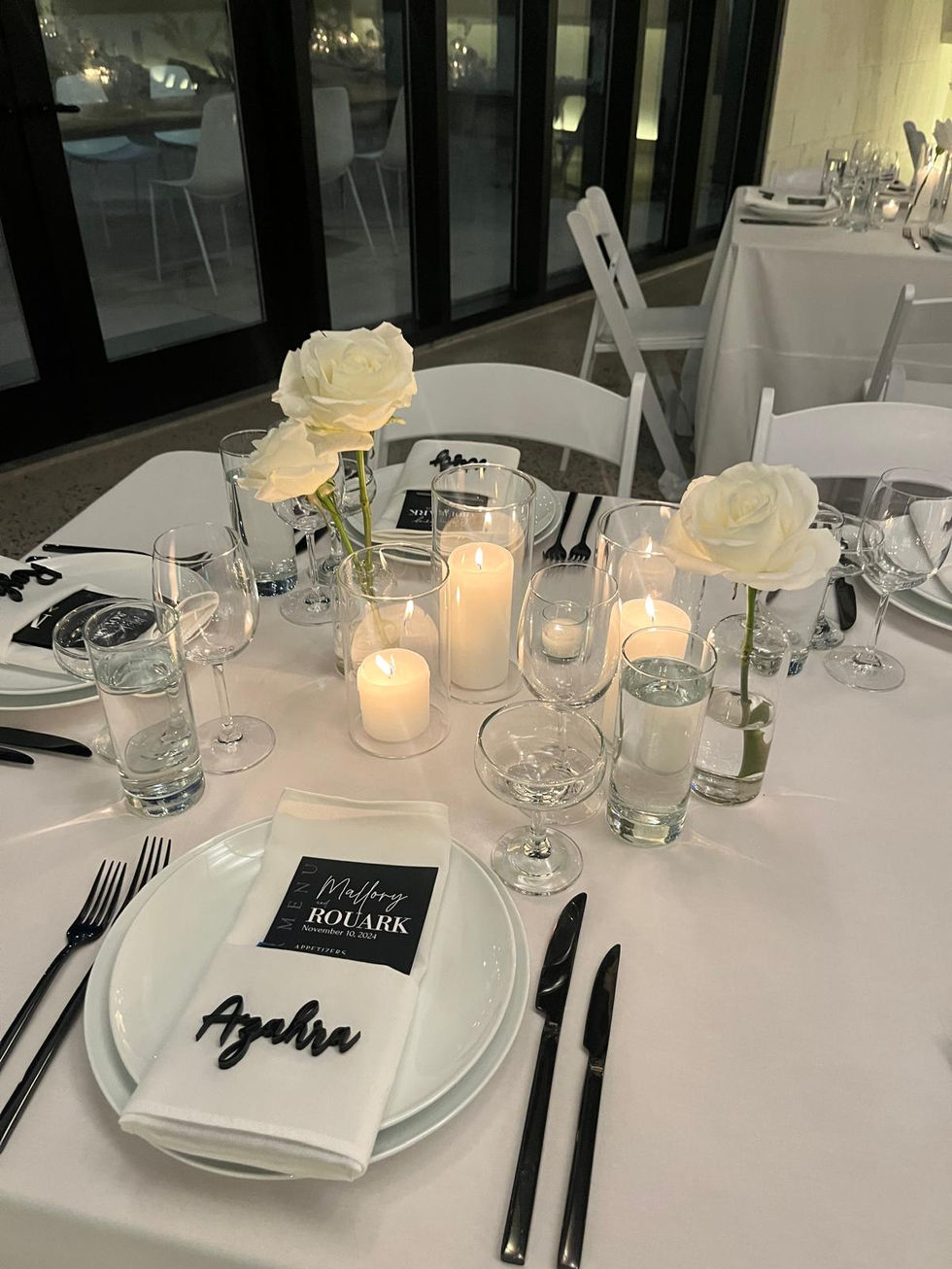 a table set for a wedding reception with white roses and candles