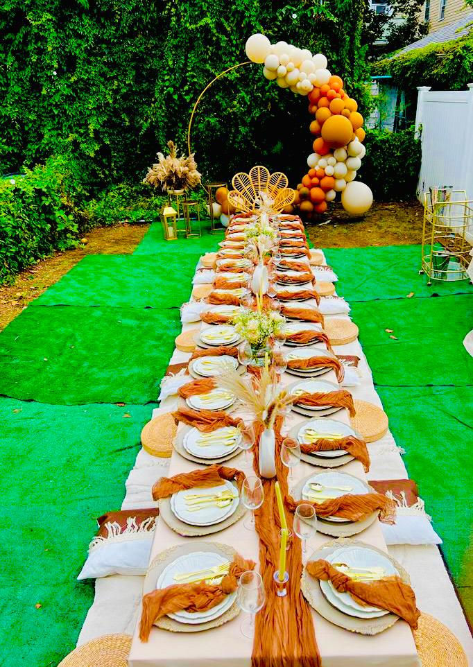 a long table with plates , utensils , and balloons on it .