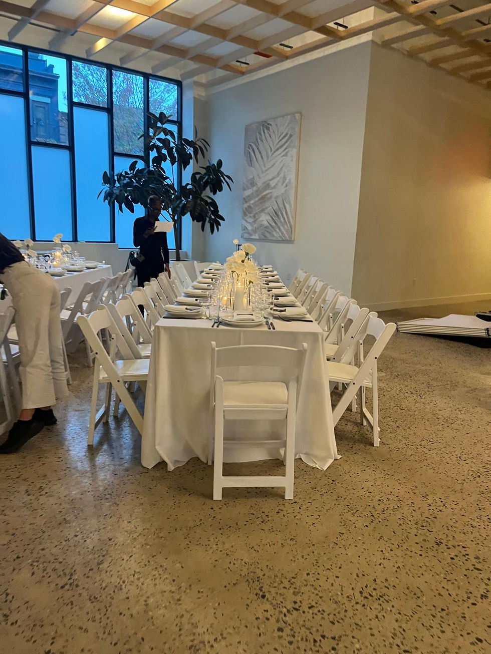 a long table with a white table cloth and white folding chairs