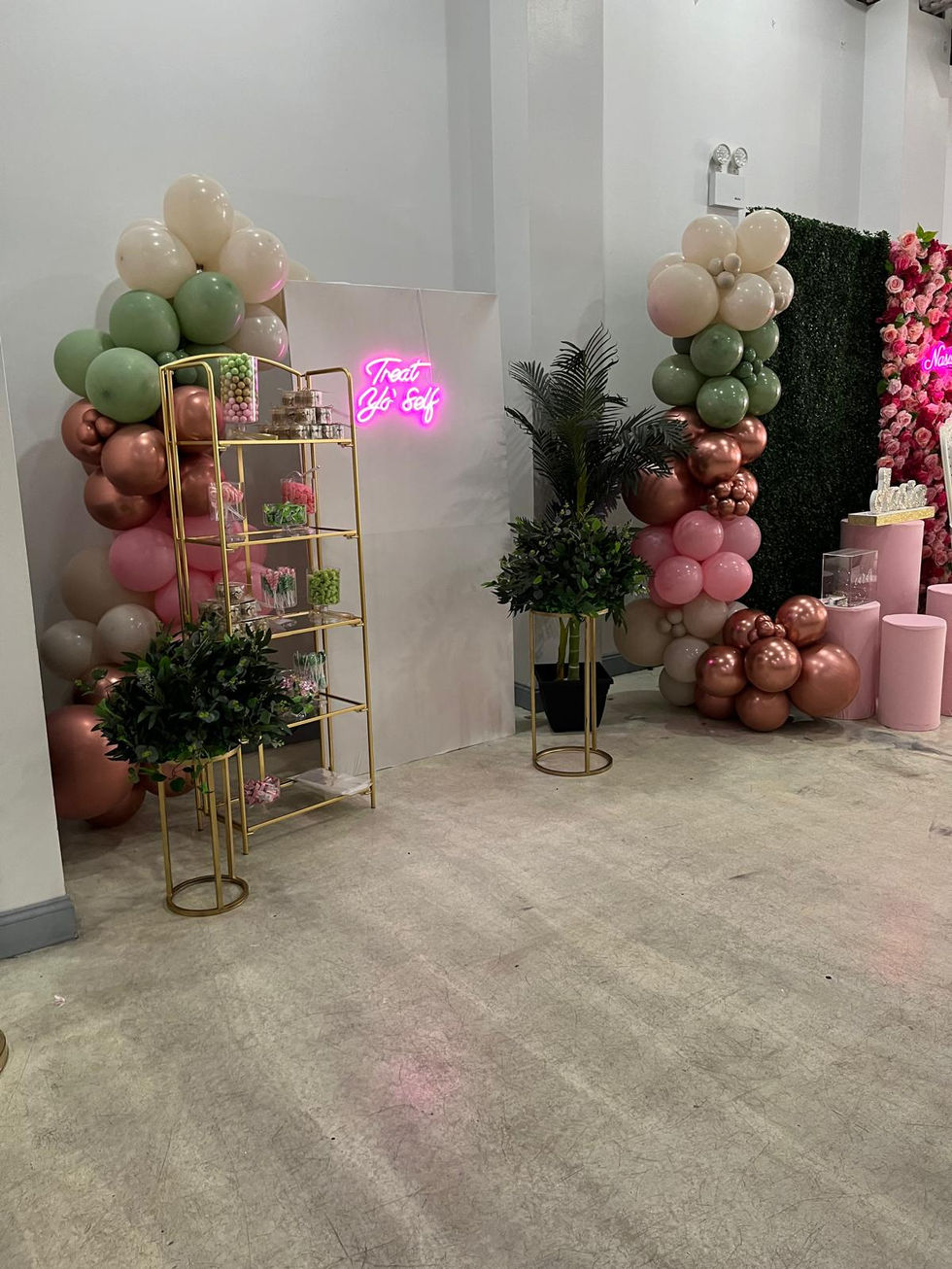 a room decorated with balloons and a neon sign that says treat go self