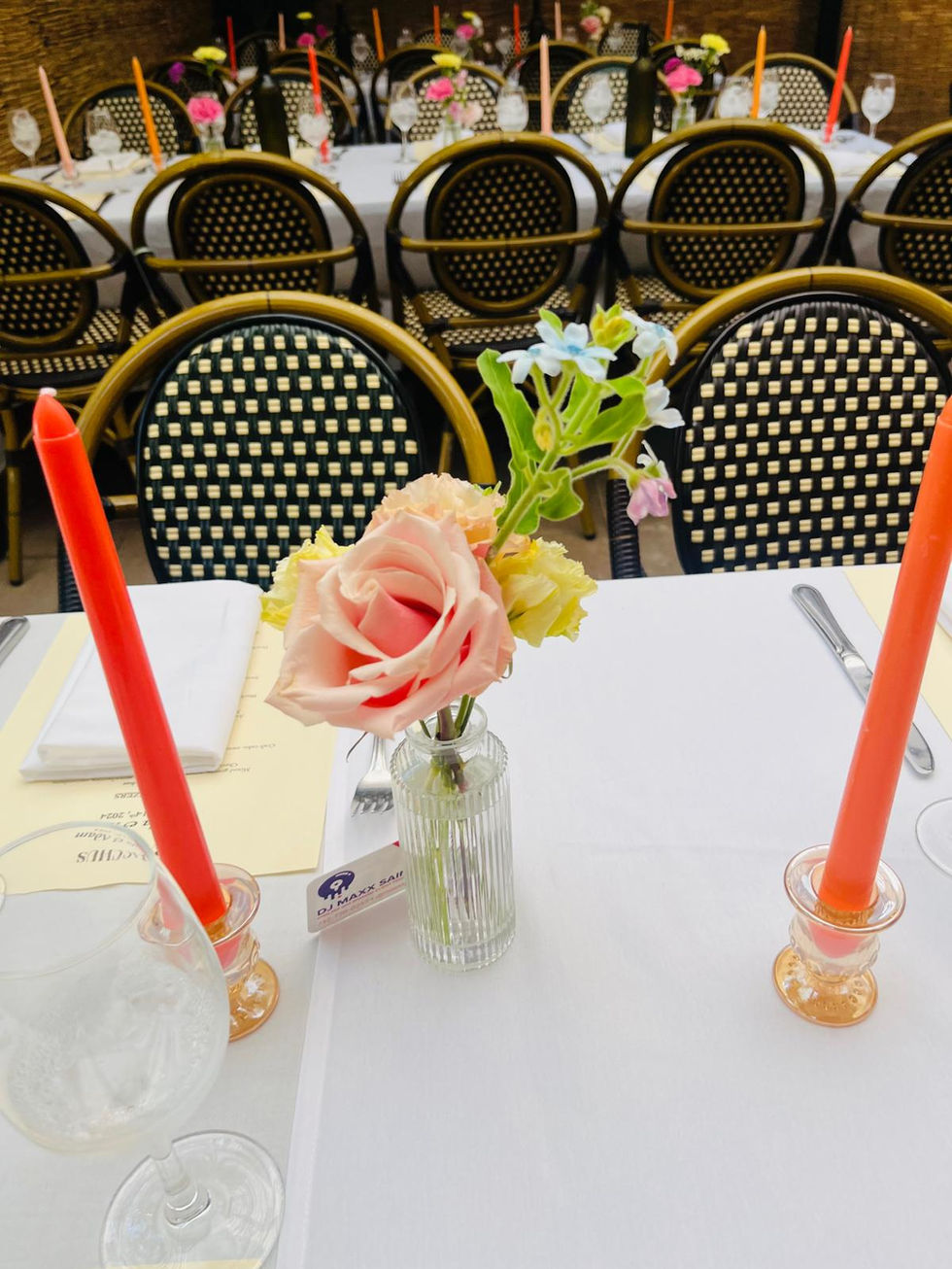 a small vase of flowers sits on a table next to two red candles