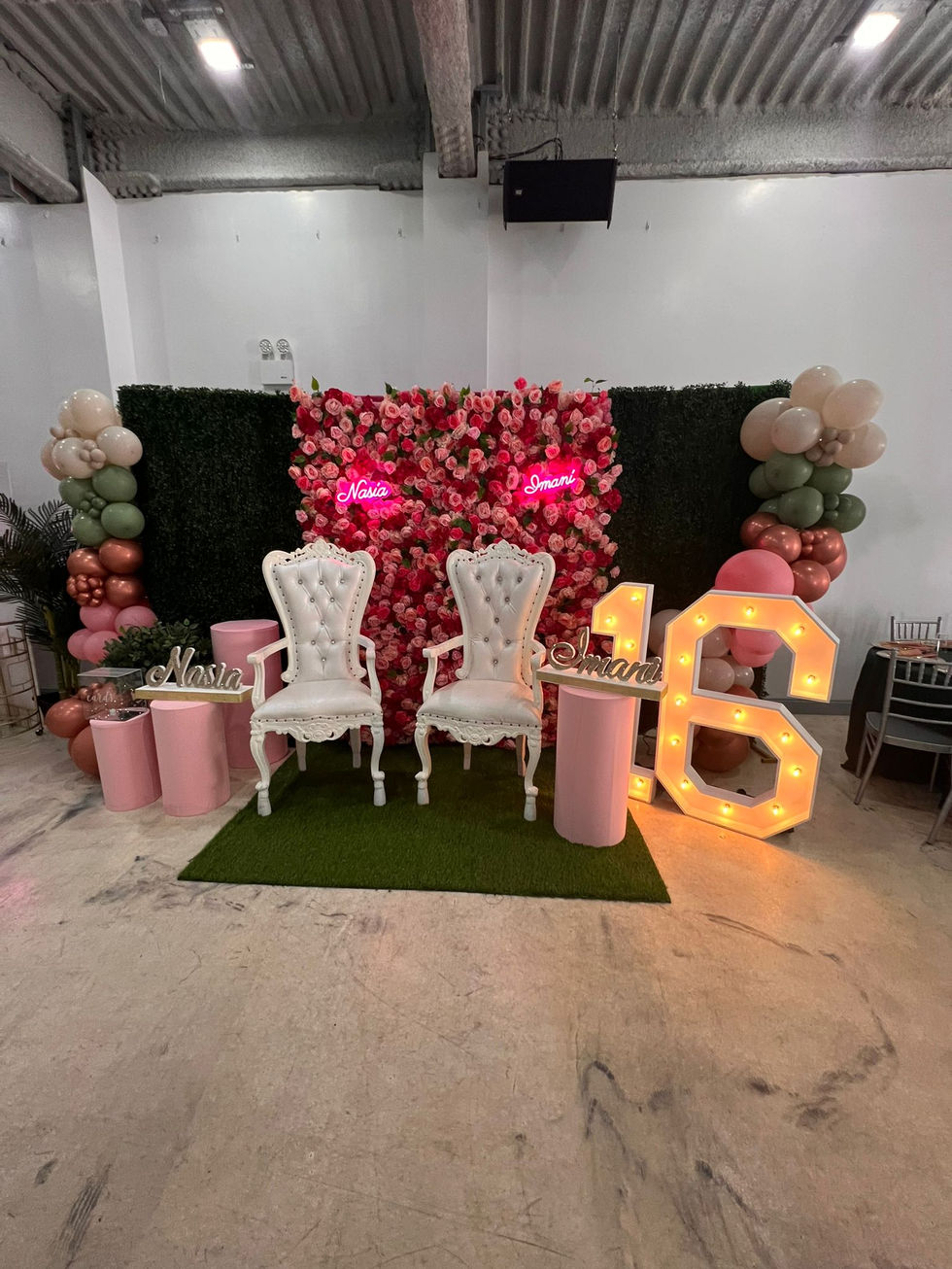 two chairs are sitting in front of a wall with flowers and balloons