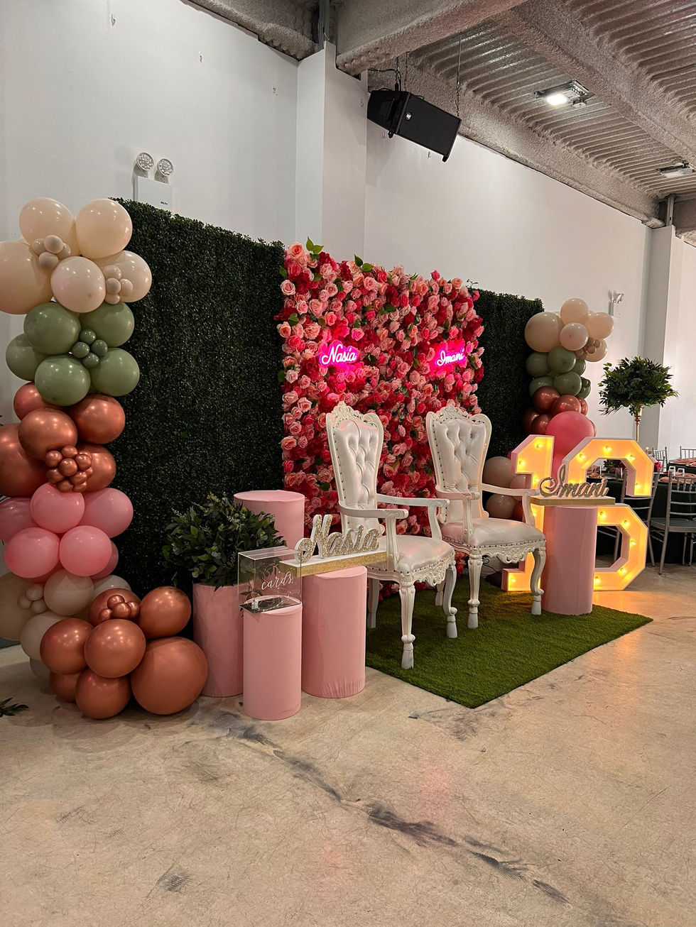 two chairs are sitting in front of a wall with flowers and balloons