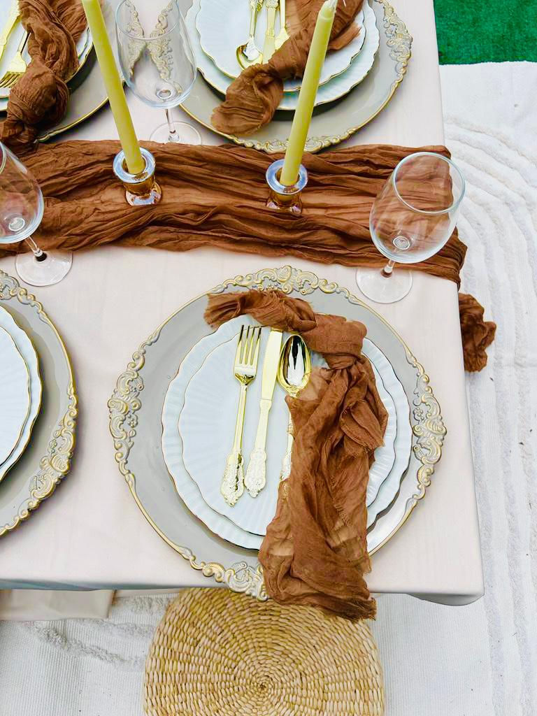 a table setting with plates , silverware , candles and wine glasses .