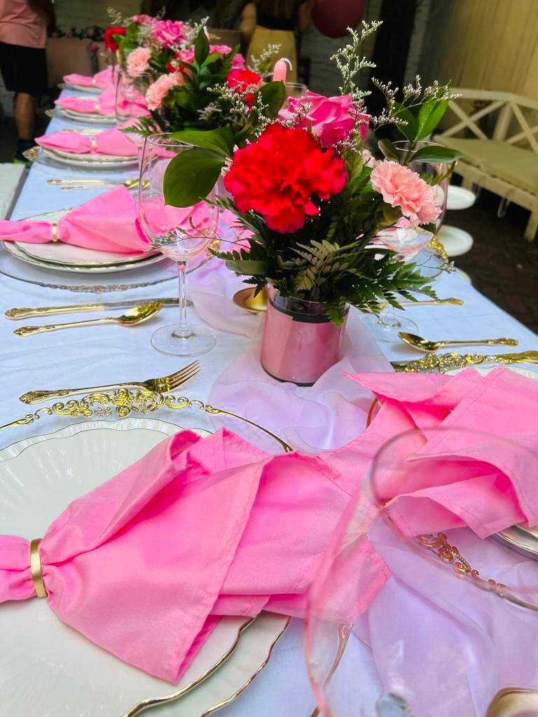 a table with pink napkins and flowers on it