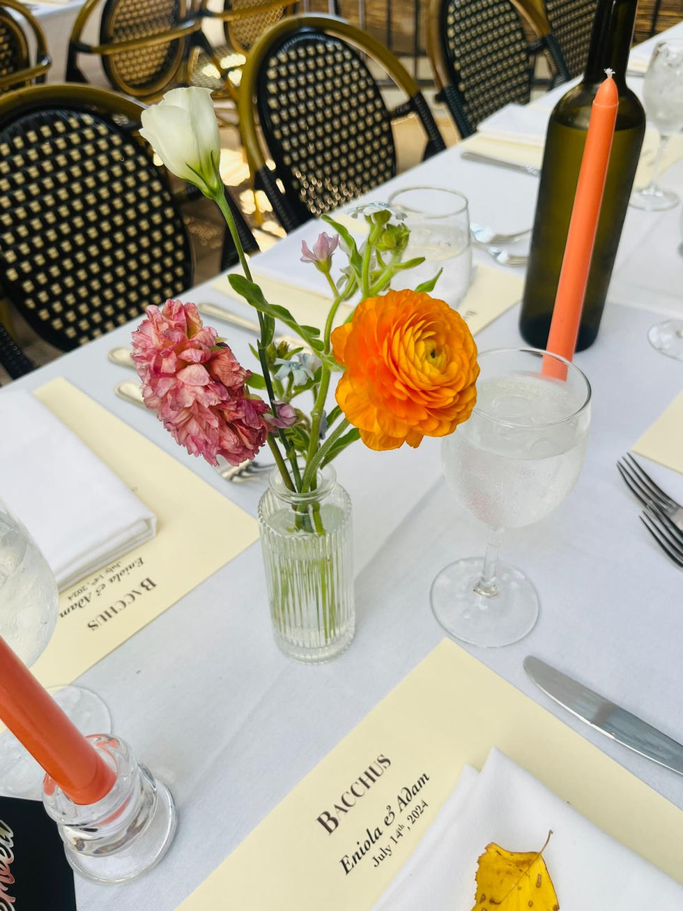 flowers in a vase on a table with a menu that says bacchus